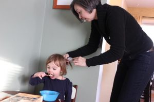 Jennifer Popple brushes her daughter, Anya’s hair while eating breakfast and getting ready for school. Popple has two children with Samantha Keehn, a professor in the music department.  Photo by Madison Rodgers.